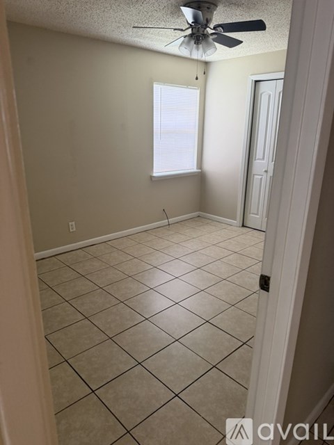 A room with a ceiling fan and tile flooring.