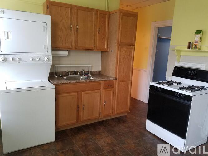A kitchen with a white fridge, wooden cabinets, and a black stove.