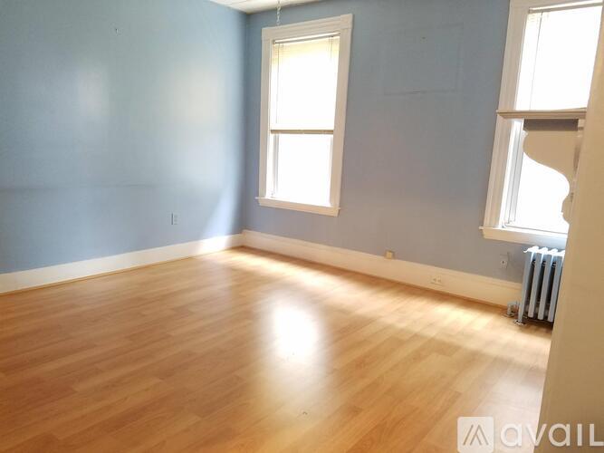 A room with wooden flooring and two windows.