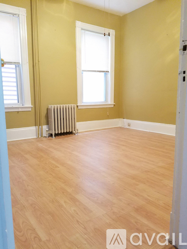 A room with wooden floors and two windows.