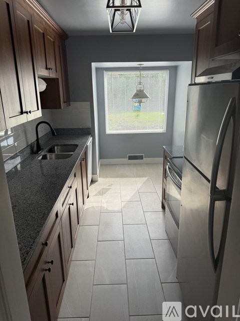 A kitchen with a refrigerator, sink, and cabinets.