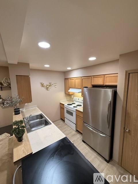 A kitchen with a stainless steel refrigerator and wooden cabinets.