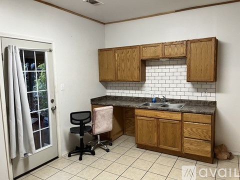A kitchen with wooden cabinets and a black chair.