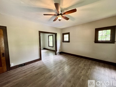 A room with a ceiling fan and wooden flooring.