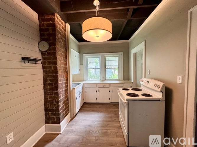 A kitchen with a brick column and a white stove top oven.