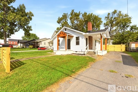 A house with a white exterior and a red car parked in front.
