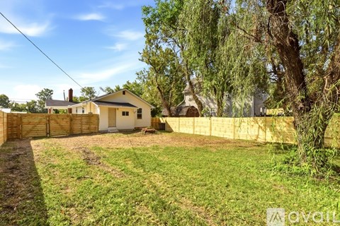 A house with a fence and a tree in front of it.