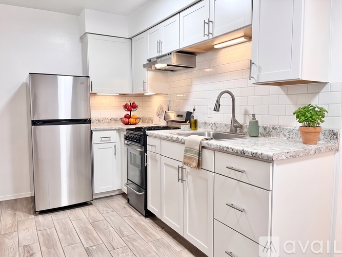 A kitchen with white cabinets and a marble countertop.