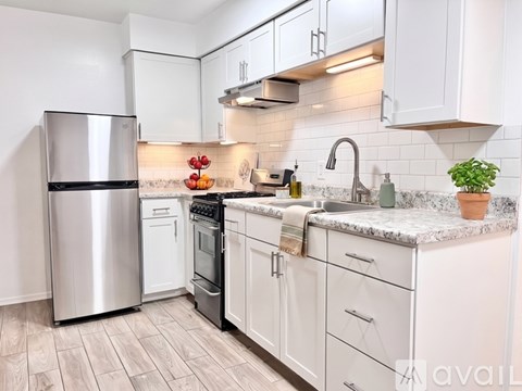 A kitchen with white cabinets and a marble countertop.