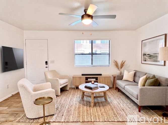 A living room with a grey couch, a white chair, a coffee table and a ceiling fan.