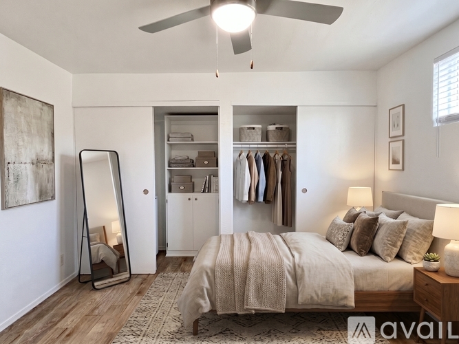 A bedroom with a large bed, a mirror, a ceiling fan, and a wardrobe.