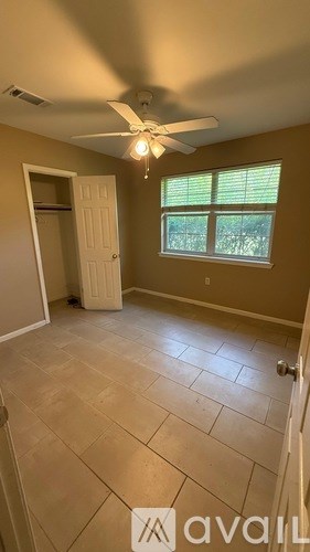 A room with a ceiling fan and a window with blinds.