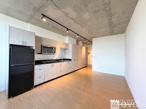 A modern kitchen with black appliances and wooden floors.