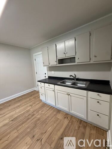 A kitchen with white cabinets and a black countertop.