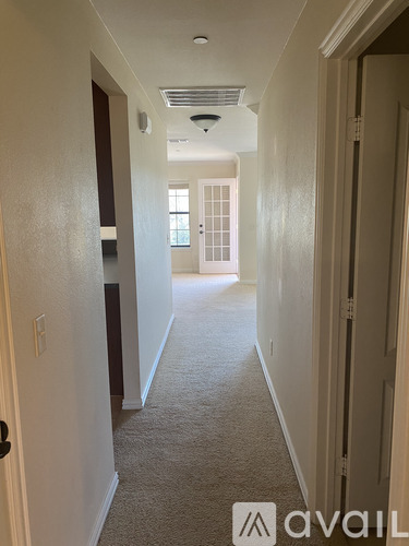 A hallway with a carpeted floor and white walls.