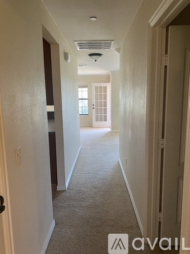 A hallway with a carpeted floor and white walls.