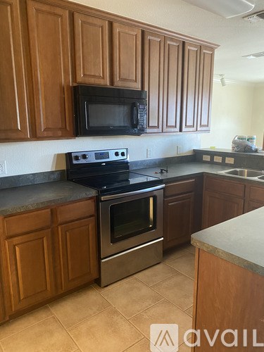 A kitchen with wooden cabinets and a black microwave above the stove.
