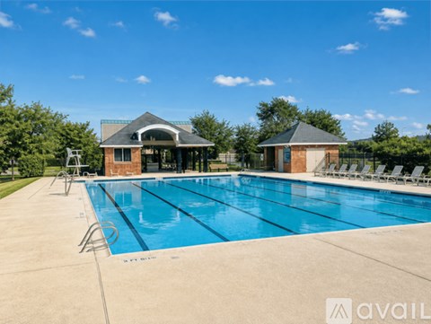 A large outdoor swimming pool with a pavilion and lounge chairs.