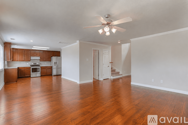 A spacious living room with hardwood floors and a ceiling fan.