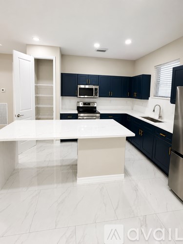 A modern kitchen with a white island and dark blue cabinets.