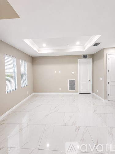 A spacious room with marble flooring and white walls.