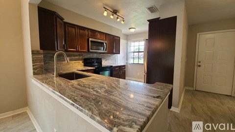 A kitchen with granite countertops and dark brown cabinets.