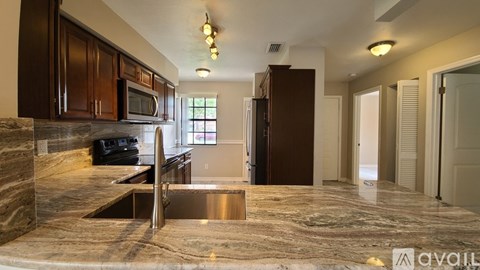 A kitchen with brown cabinets and a marble countertop.