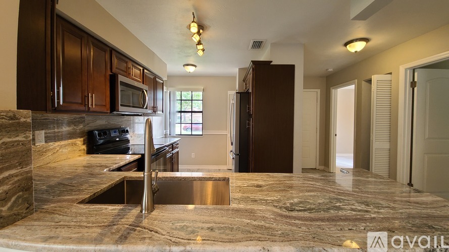 A kitchen with brown cabinets and a marble countertop.