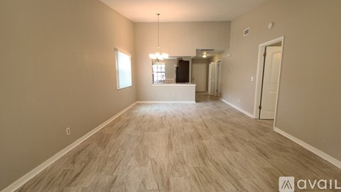 A spacious room with wooden flooring and a chandelier hanging from the ceiling.