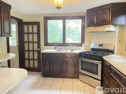 A kitchen with dark wood cabinets and a white stove top oven.
