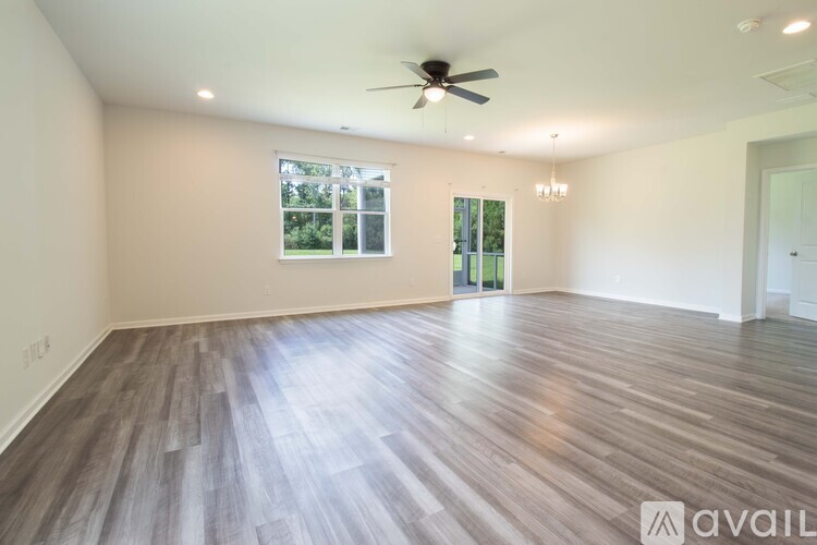 A spacious room with wooden flooring and a ceiling fan.