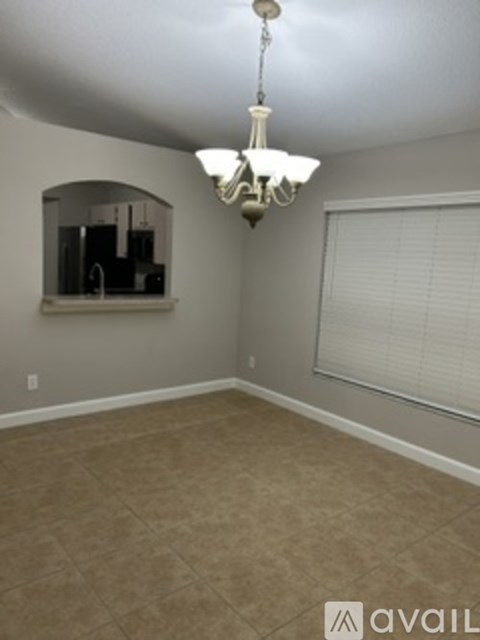 A room with a chandelier and a window with blinds.