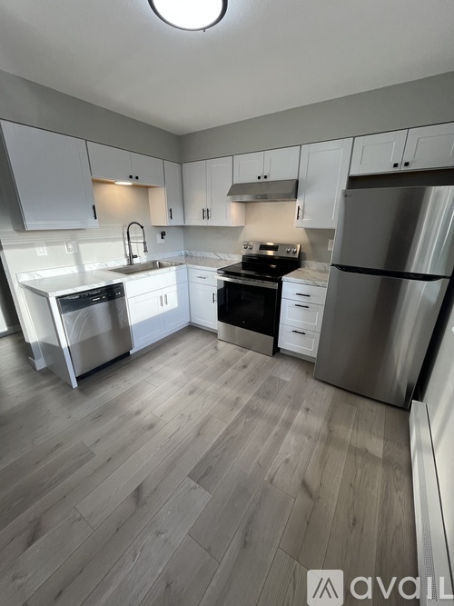 A kitchen with white cabinets and a wooden floor.