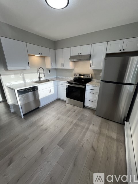 A kitchen with white cabinets and a wooden floor.