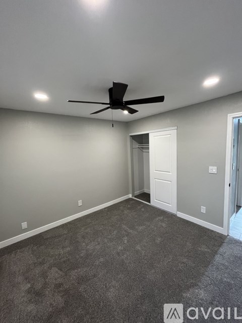 A room with a ceiling fan and carpeted floor.