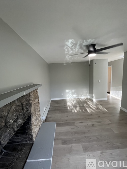 A modern living room with a stone fireplace and a fan on the ceiling.