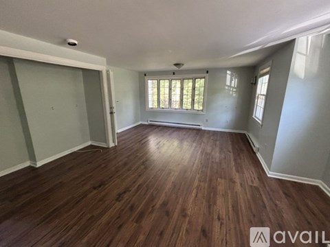 A room with wooden flooring and a window with blinds.