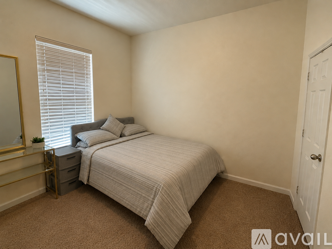 A bedroom with a bed, nightstand, and window with blinds.