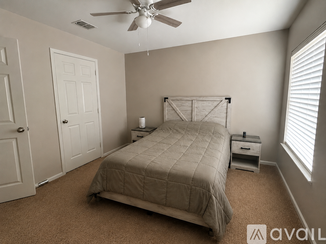 A bedroom with a bed, nightstand, and a ceiling fan.