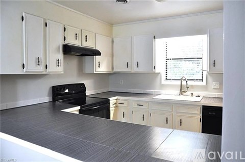 A kitchen with white cabinets and black appliances.