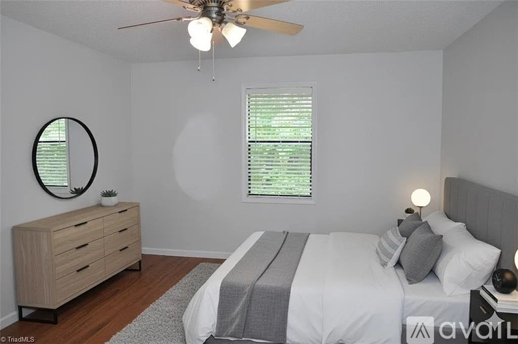 A bedroom with a bed, dresser, and window with blinds.