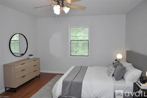 A bedroom with a bed, dresser, and window with blinds.