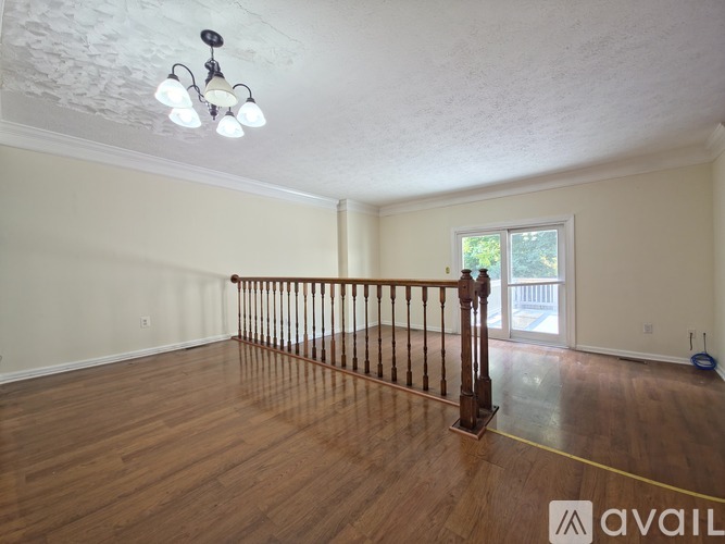 A room with wooden floors and a window with a view of trees.