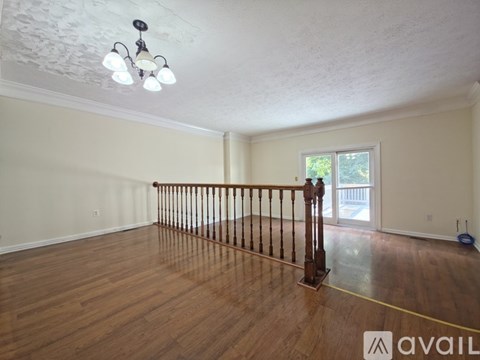 A room with wooden floors and a window with a view of trees.