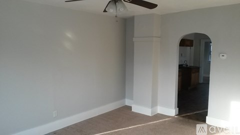 A room with a ceiling fan and a doorway leading to another room.