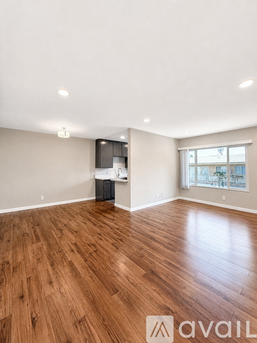 A room with wooden flooring and a window overlooking a cityscape.