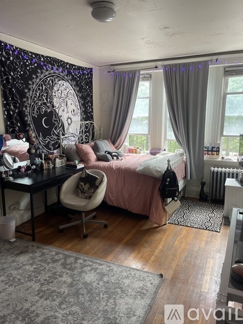 A room with a desk and a bed with a pink blanket.