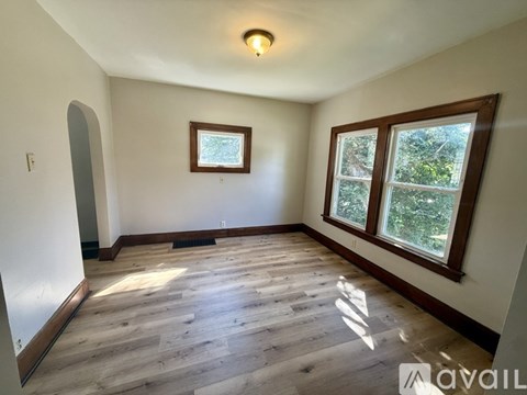 A room with wooden flooring and a window showing greenery outside.