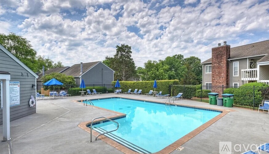 A pool surrounded by chairs and a fence.