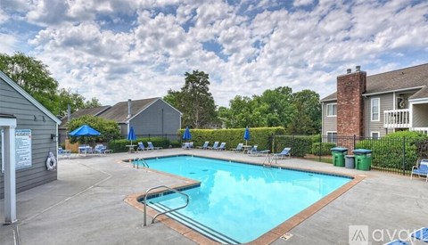 A pool surrounded by chairs and a fence.